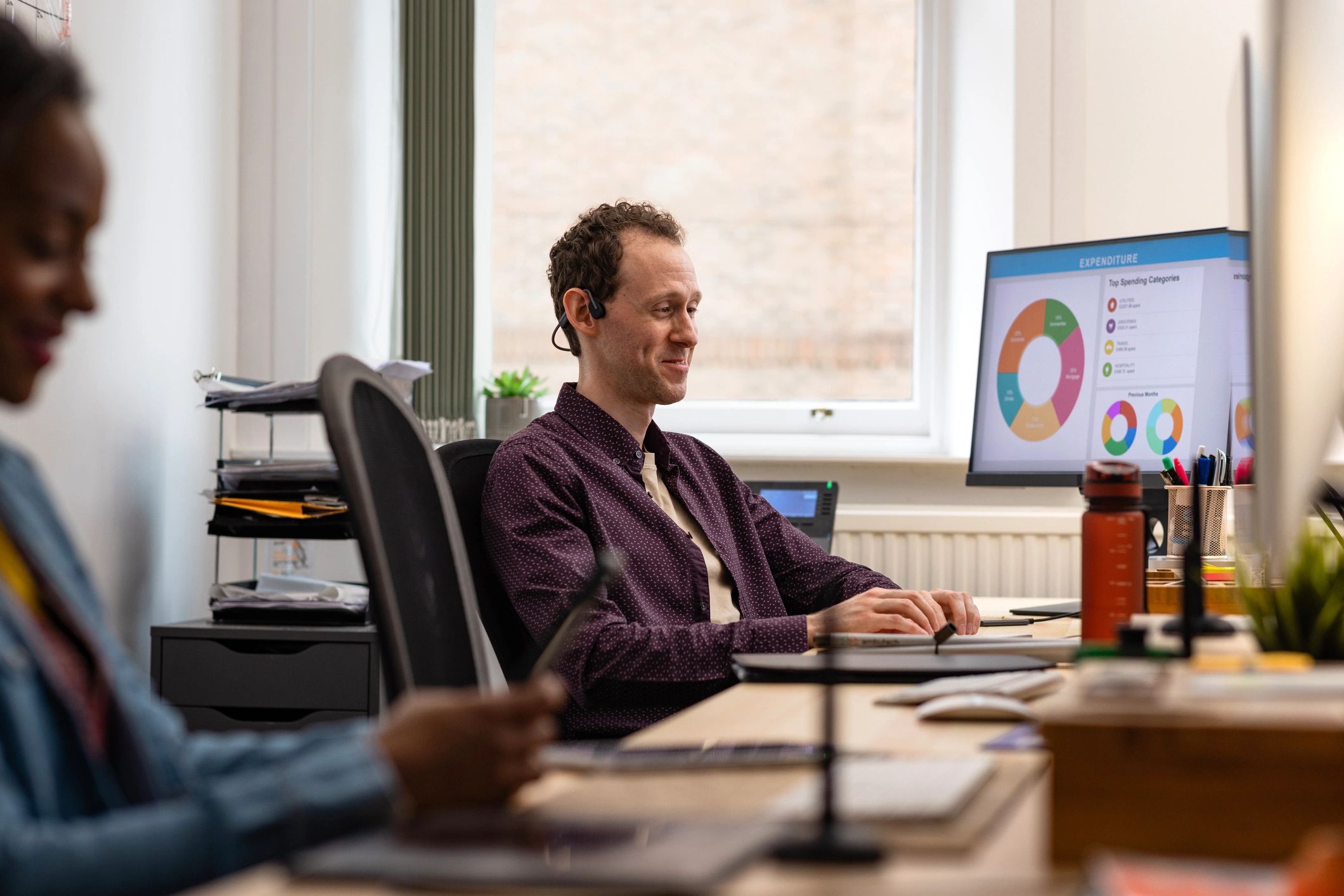 IT support engineer assisting a colleague at a computer